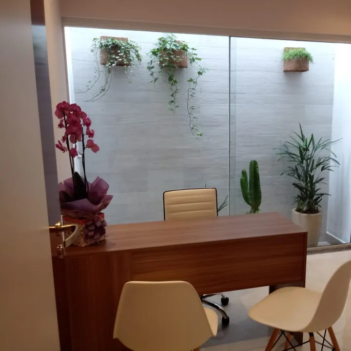 Consultório médico com mesa, orquídea e jardim de inverno